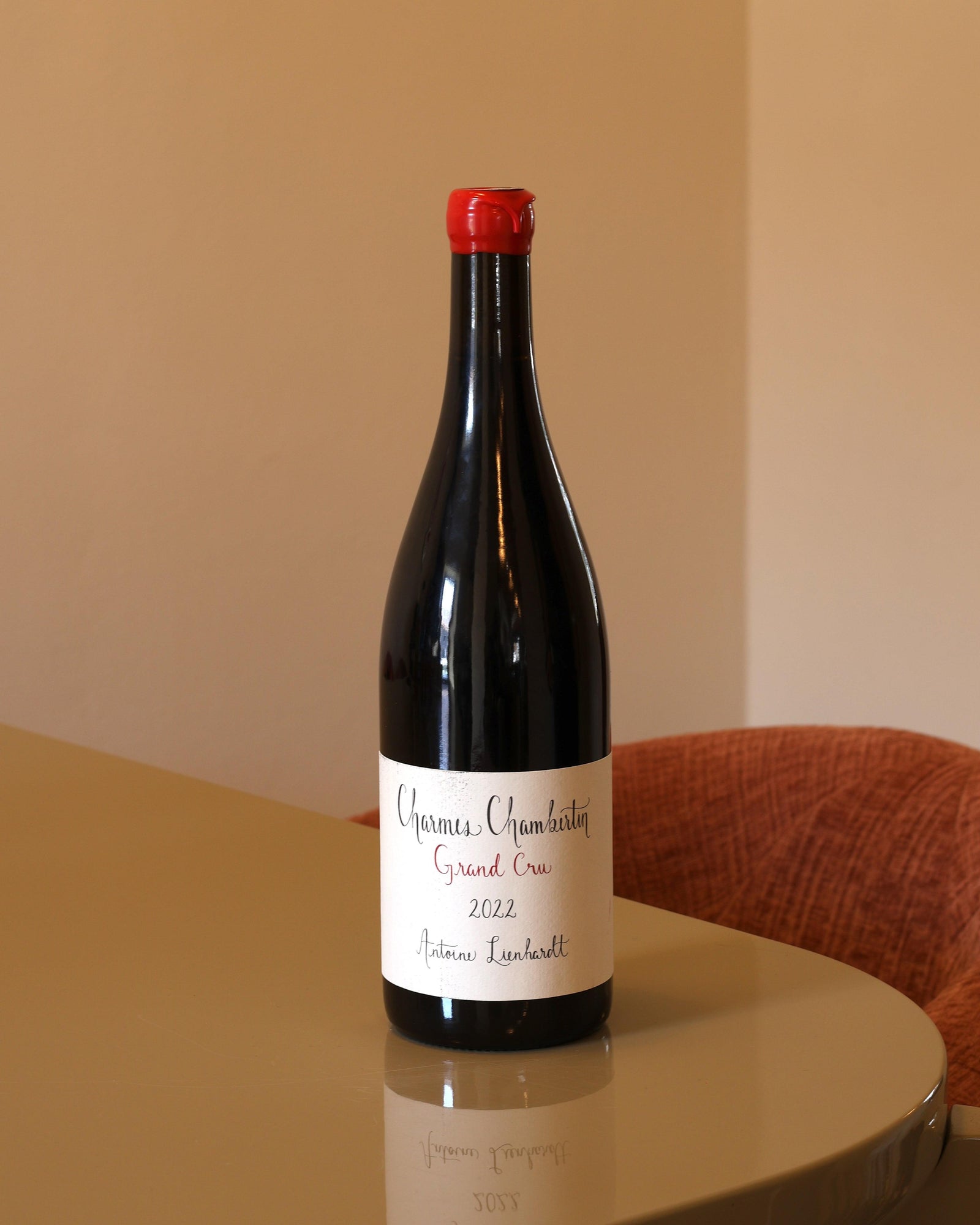 Bottiglia di vino rosso Antoine Lienhardt Charmes-Chambertin Grand Cru 2022 con tappo in ceralacca rossa su tavolo lucido.