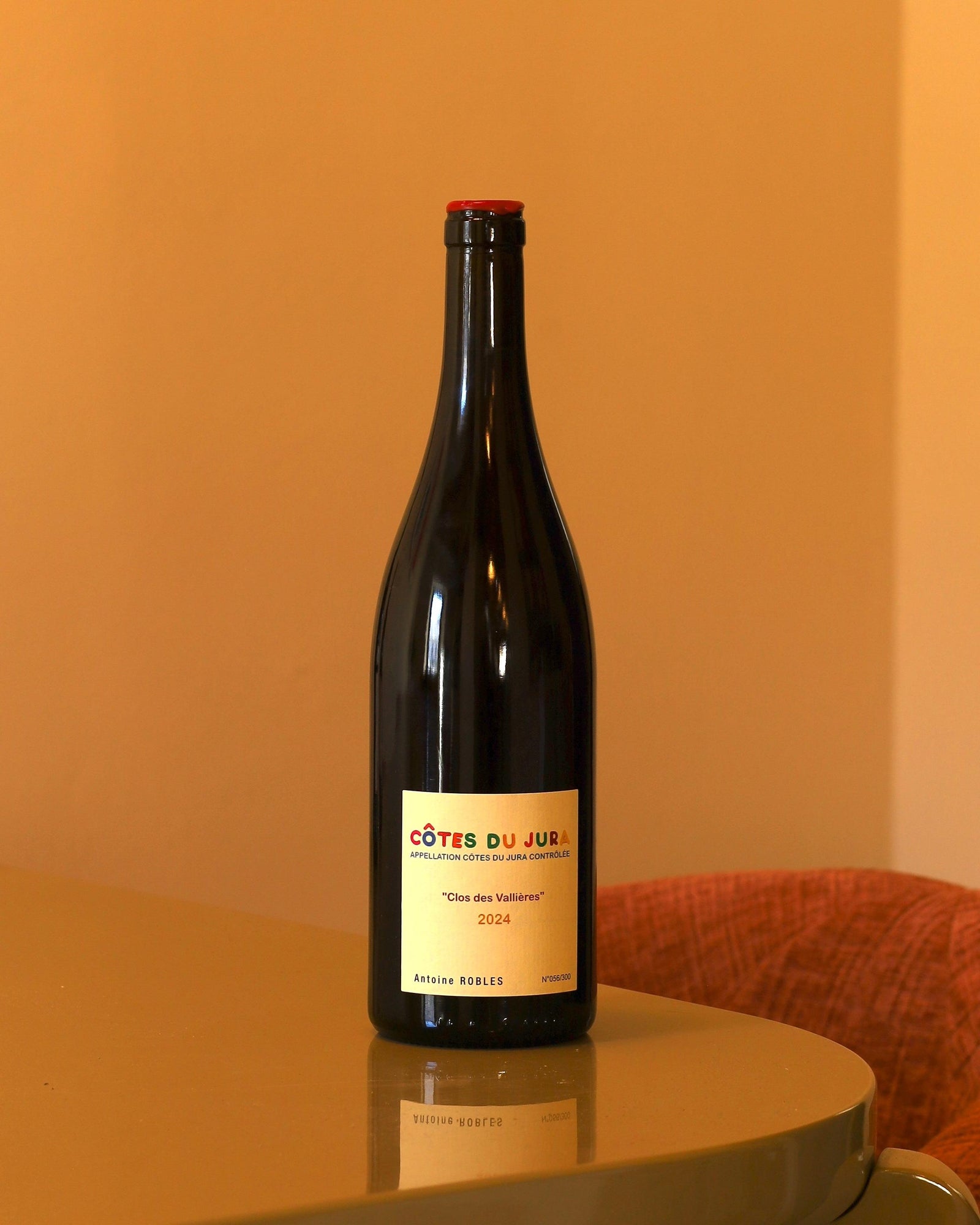 Bottiglia di vino rosso Antoine Robles Trousseau Clos des Vallières 2024 con etichetta chiara su tavolo riflettente.