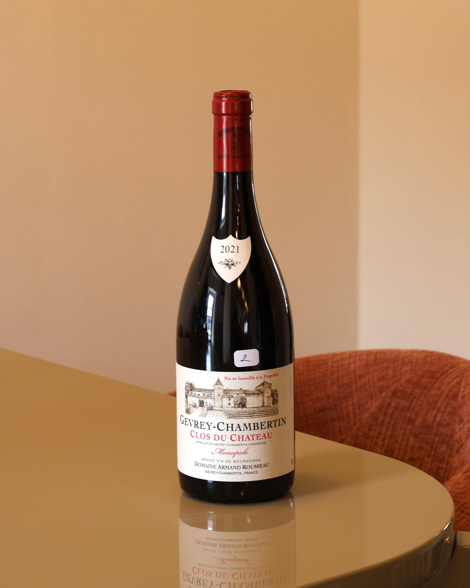 Bottiglia di vino rosso Armand Rousseau Gevrey-Chambertin Clos du Chateau 2021 su tavolo lucido.