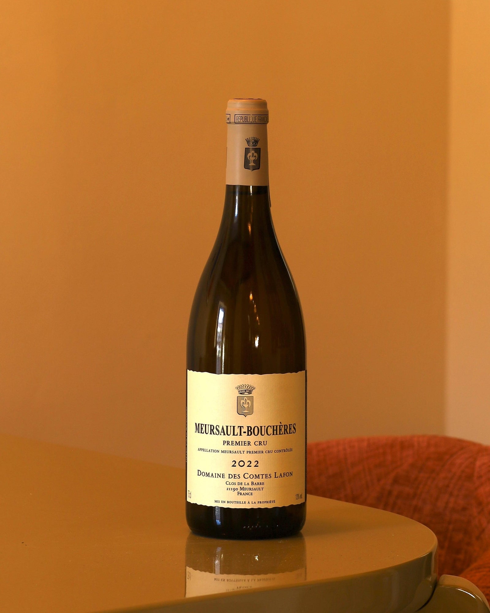 Bottiglia di vino bianco Comtes de Lafon Meursault-Bouchères Premier Cru 2022 su tavolo lucido.