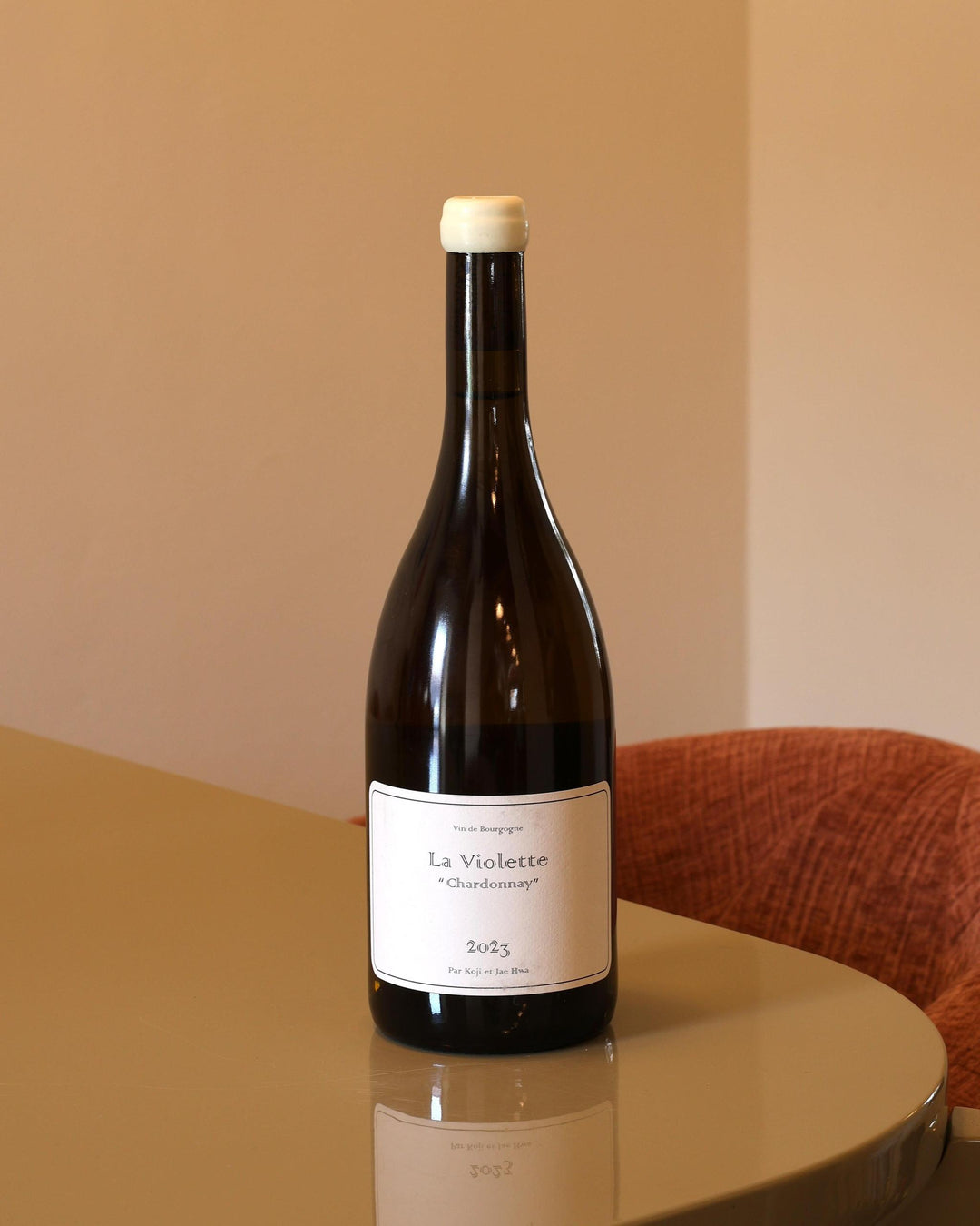 Bottiglia di vino bianco Domaine Koji et Jae Hwa La Violette Chardonnay 2023 con etichetta minimalista su tavolo lucido.