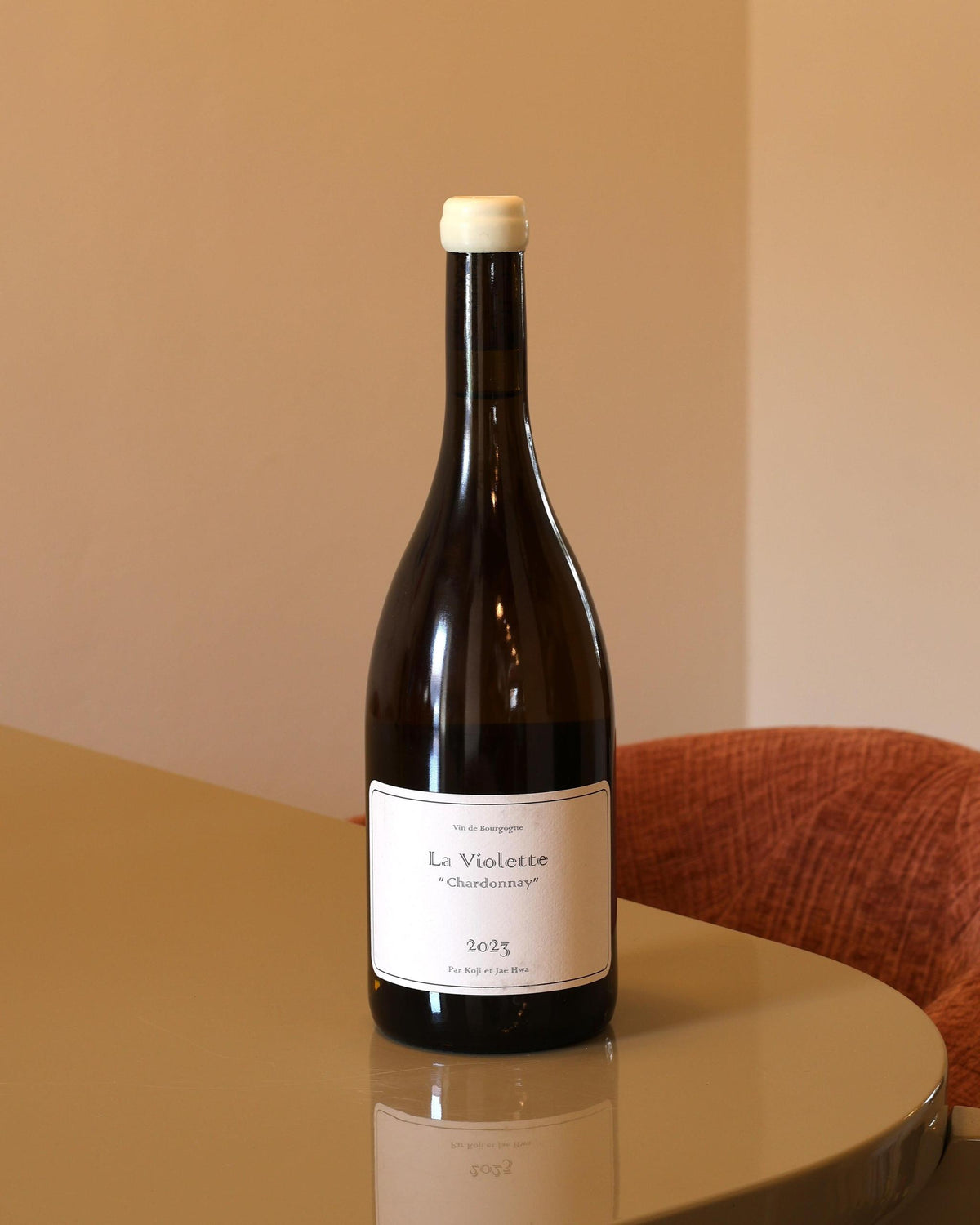 Bottiglia di vino bianco Domaine Koji et Jae Hwa La Violette Chardonnay 2023 con etichetta minimalista su tavolo lucido.