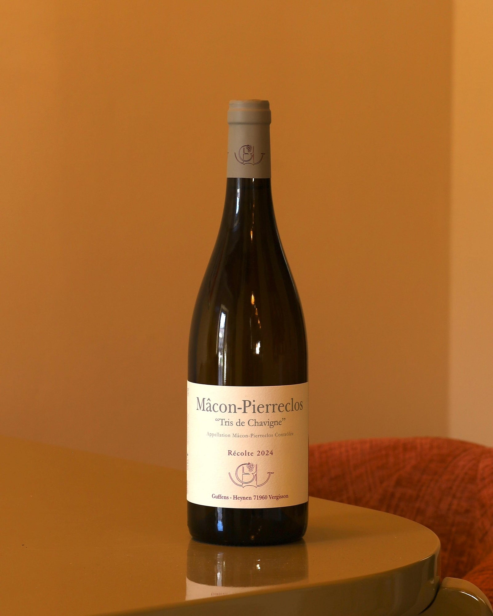 Bottiglia di vino bianco Guffens-Heynen Mâcon-Pierreclos Tris de Chavigne 2024 con etichetta chiara su sfondo ambrato.