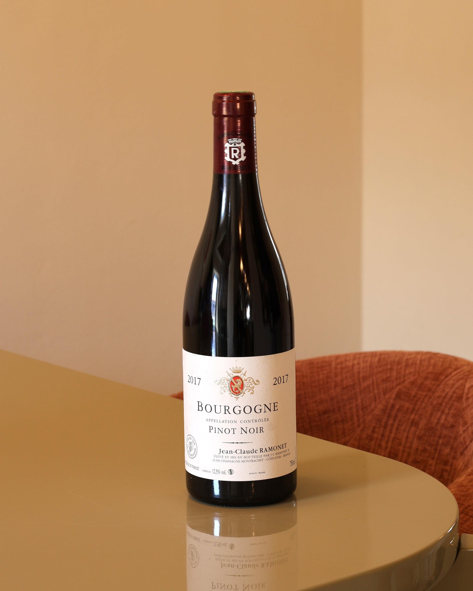 Bottiglia di Jean-Claude Ramonet Bourgogne Pinot Noir 2017 da 0,75l con etichetta classica su tavolo lucido.