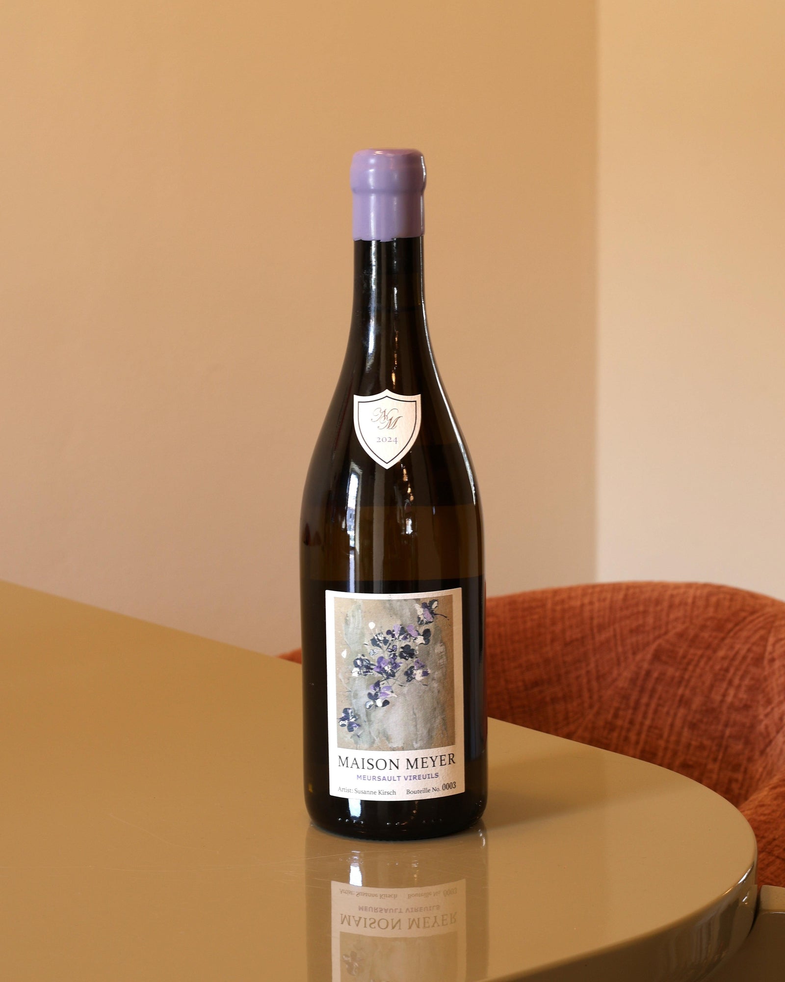 Bottiglia di vino bianco Maison Meyer Meursault Vireuils 2024 con capsula lilla su tavolo lucido.