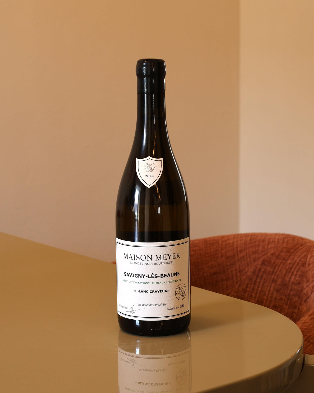 Bottiglia di vino bianco Maison Meyer Savigny-les-Beaune 2024 da 0,75l con etichetta elegante su tavolo riflettente.