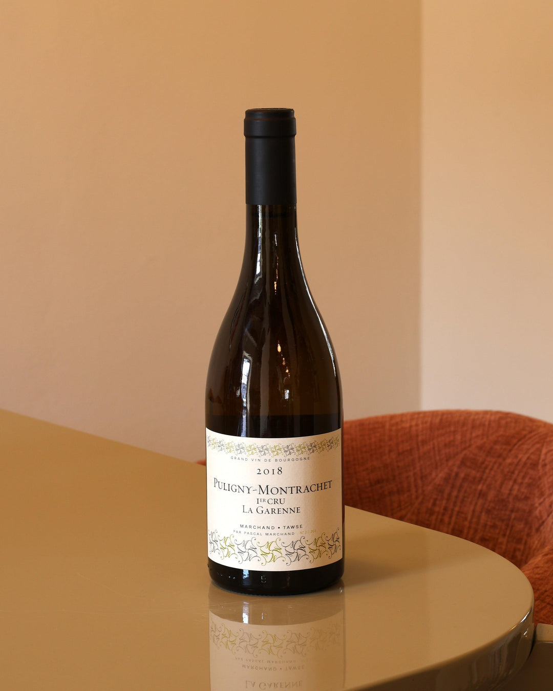 Bottiglia di vino bianco Marchand-Tawse Puligny-Montrachet 2018 0,75l con etichetta classica su tavolo riflettente.