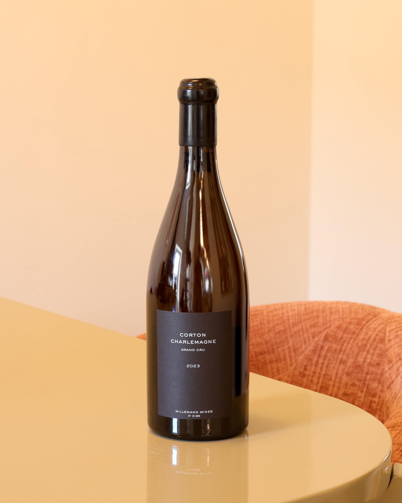 Bottiglia di vino bianco Millemann Corton Charlemagne Grand Cru 2023, 0,75l, con etichetta nera minimalista su tavolo.