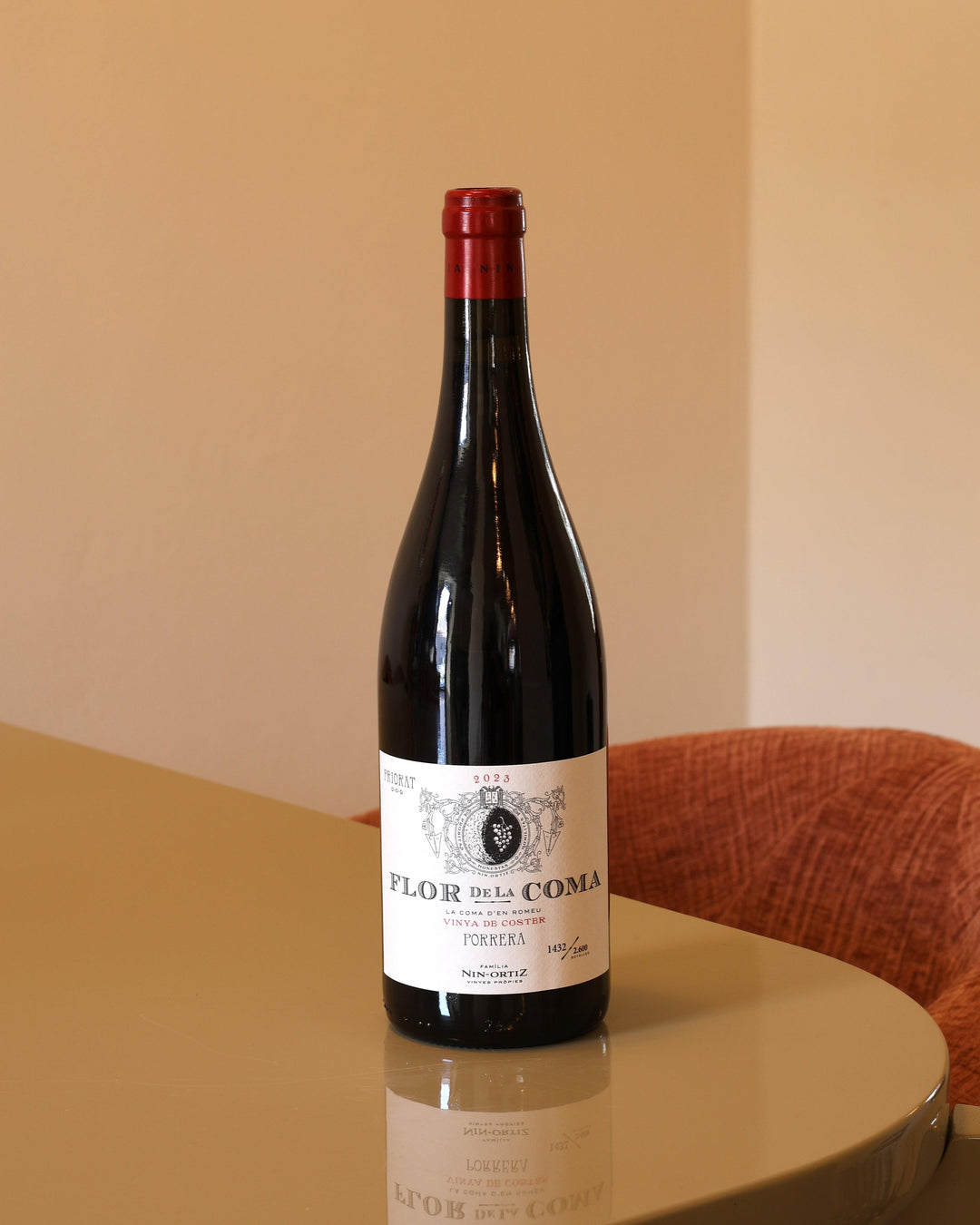 Bottiglia di vino rosso Nin Ortiz Flor de la Coma 2023 da 0,75l con etichetta chiara su tavolo riflettente.