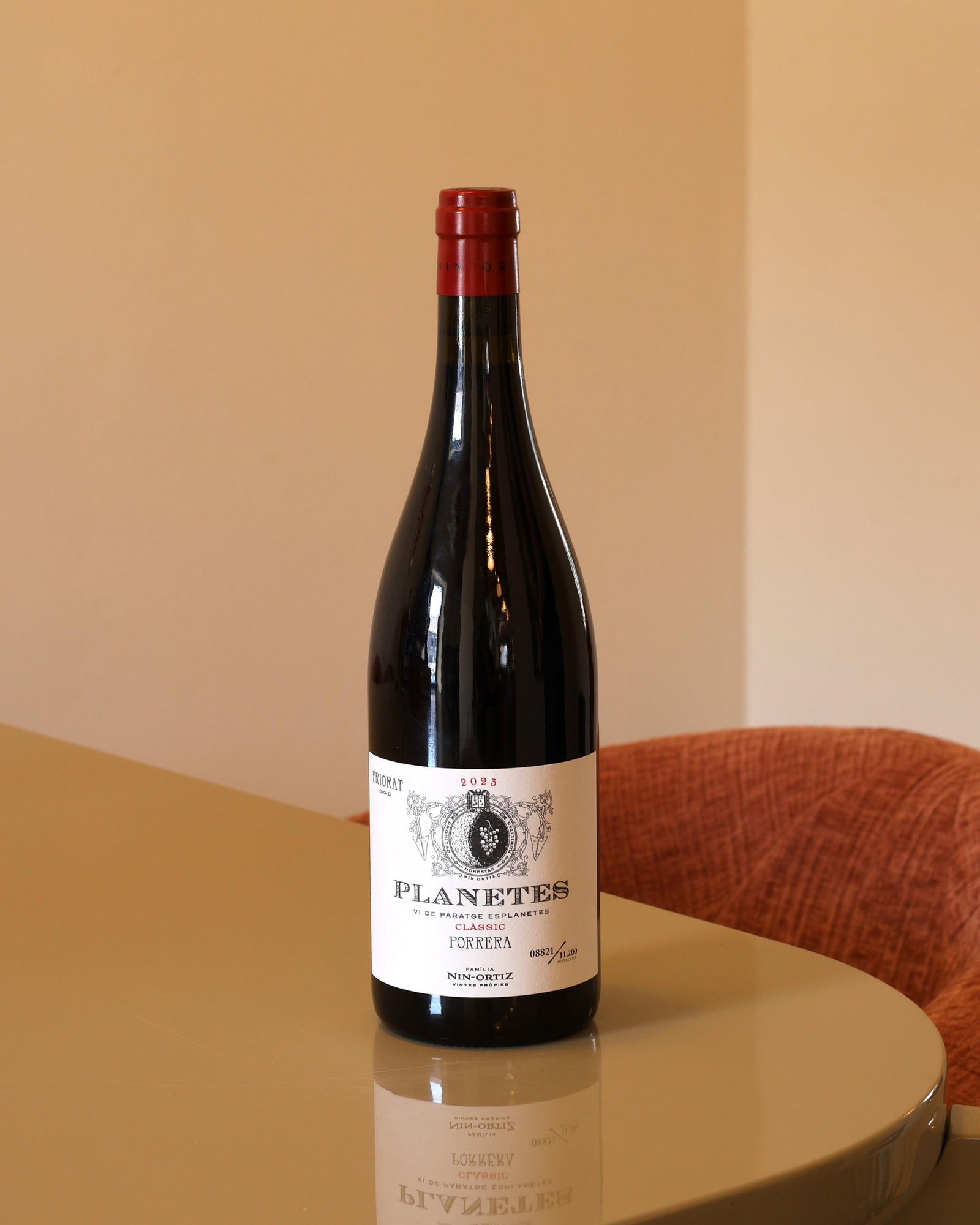 Bottiglia di vino rosso Nin Ortiz Planetes Classic 2023 da 0,75l con etichetta bianca essenziale su tavolo lucido.