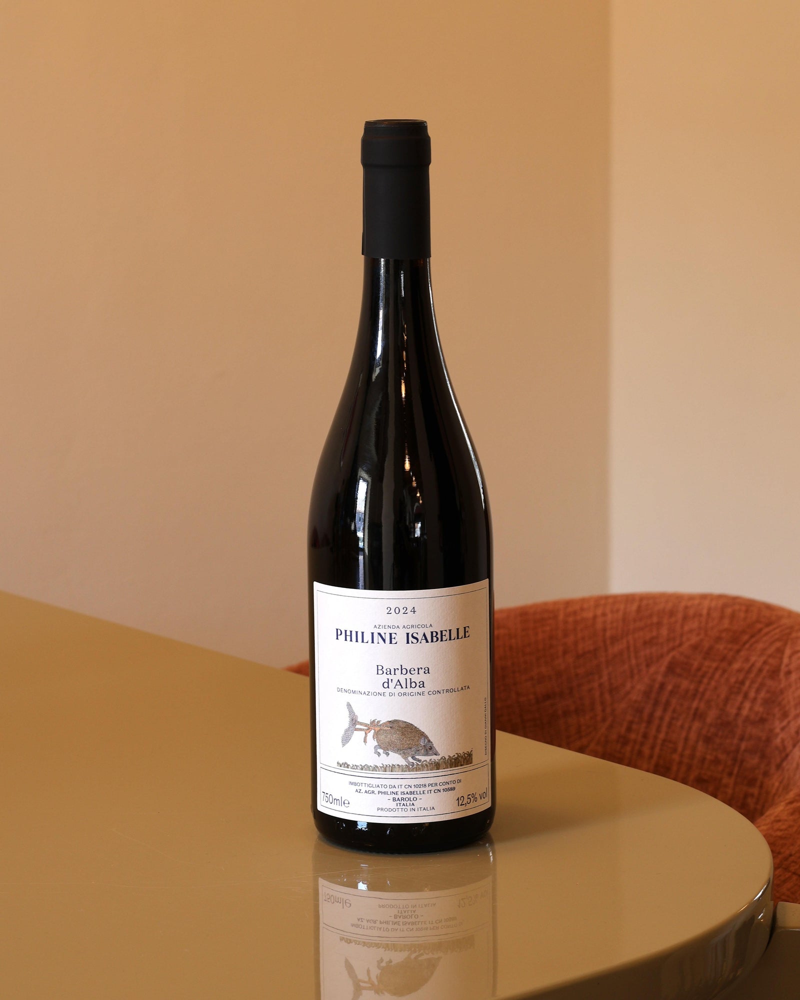 Bottiglia di vino Philine Isabelle Barbera d'Alba 2024 da 0,75l con etichetta bianca illustrata su tavolo lucido.