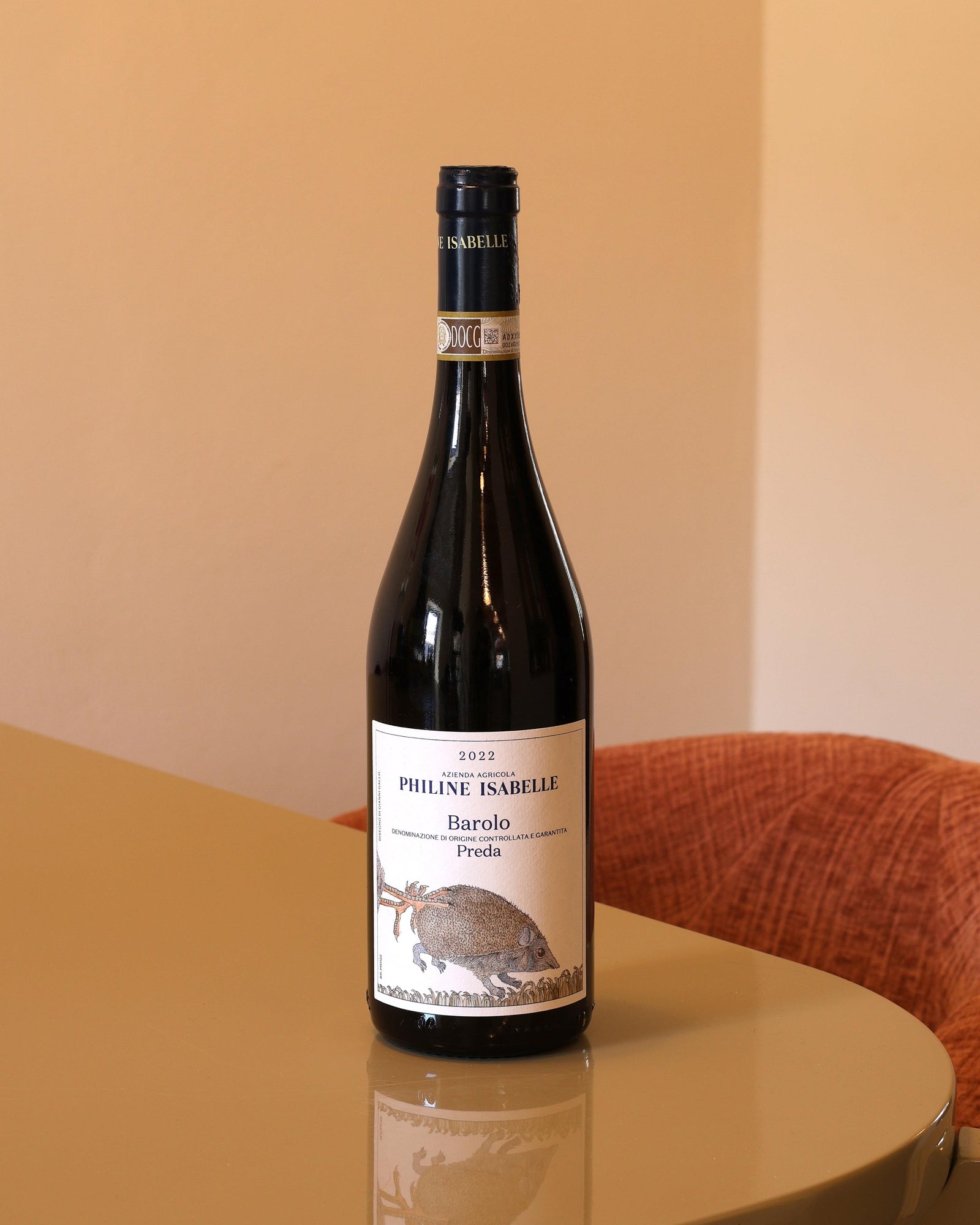 Bottiglia di vino rosso Philine Isabelle Barolo Preda 2022 con etichetta illustrata su tavolo lucido.