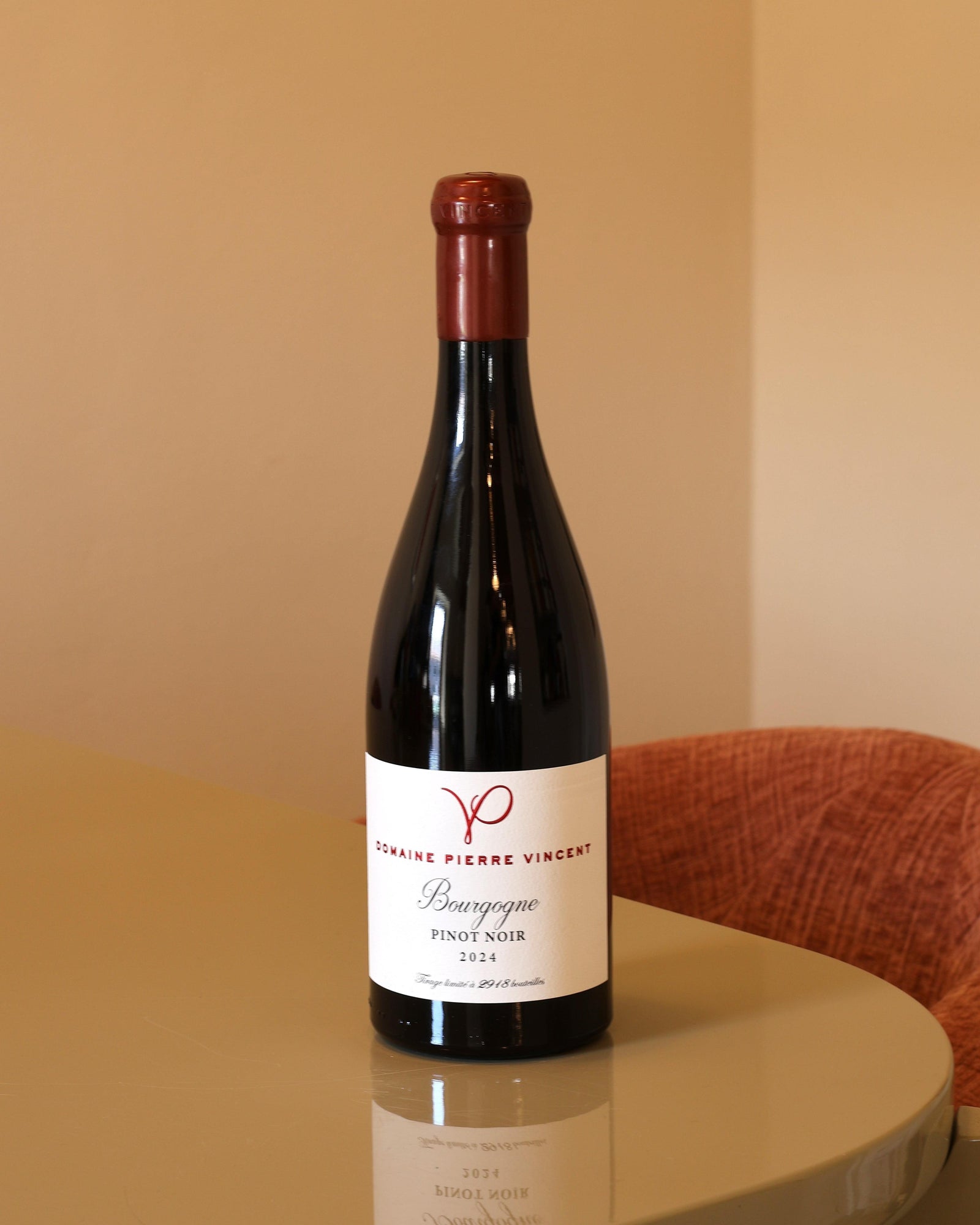 Bottiglia di vino rosso Pierre Vincent Bourgogne 2024 con etichetta bianca su tavolo lucido.