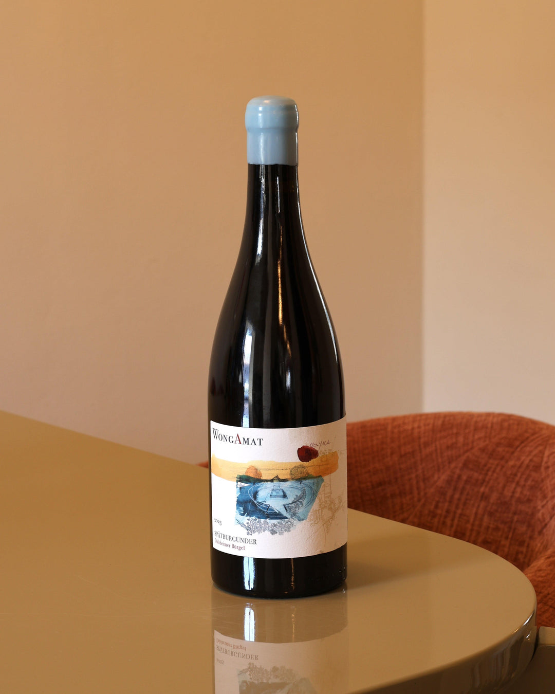 Bottiglia di vino rosso Wong Amat Burgel 2023 da 0,75l con etichetta artistica su tavolo moderno.