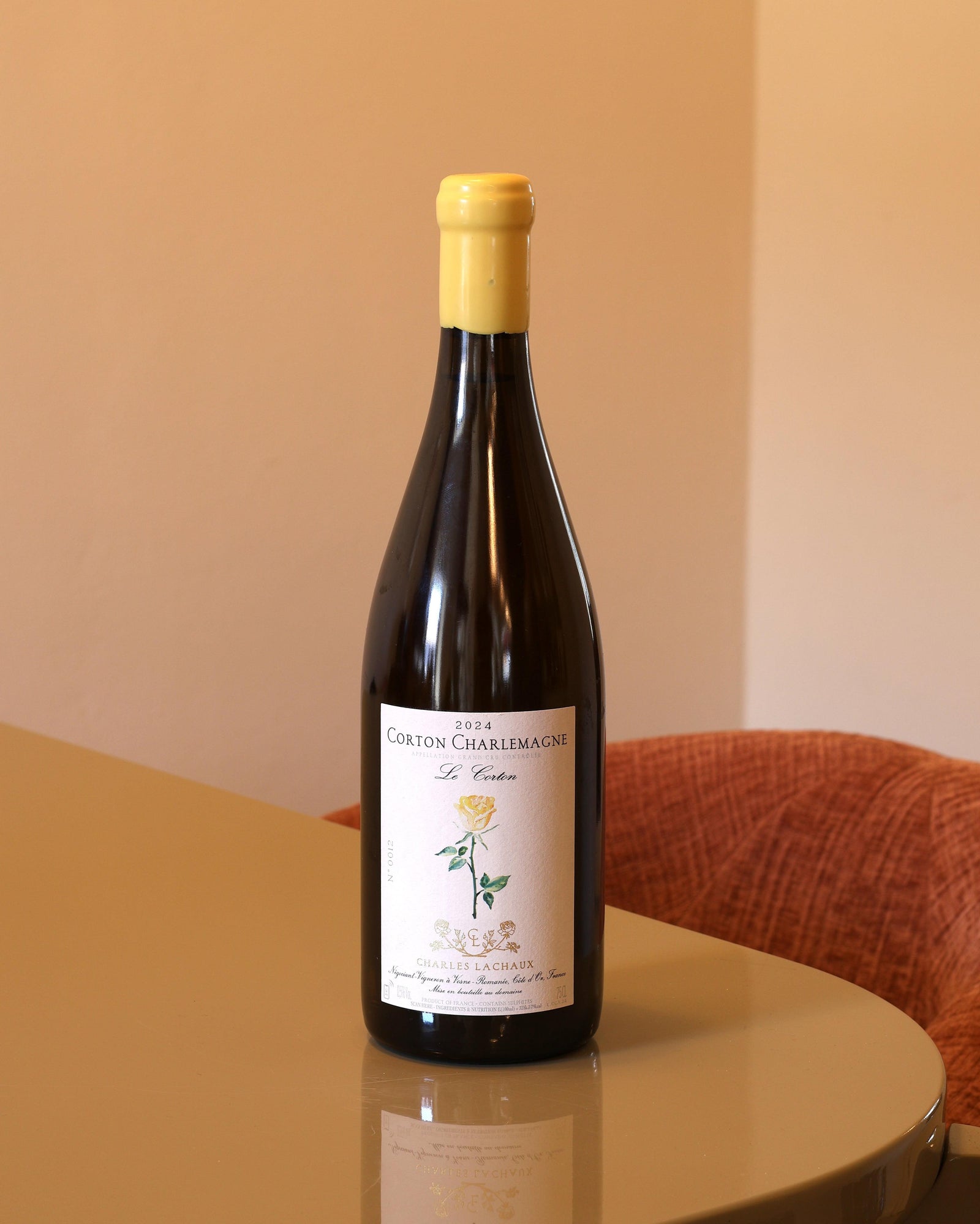 Bottiglia di vino bianco Charles Lachaux Corton Charlemagne 2024 da 0,75l con etichetta floreale su tavolo riflettente.