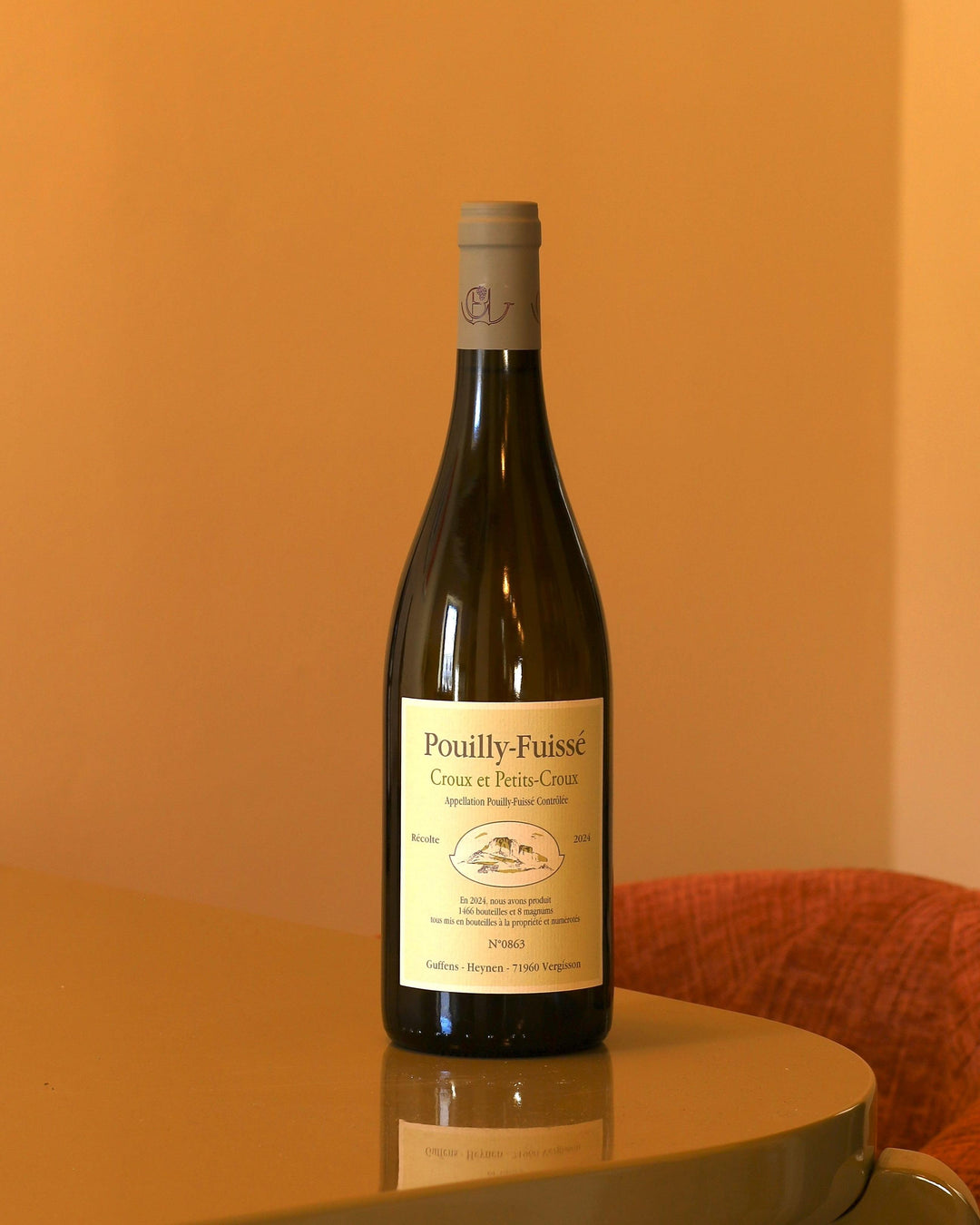 Bottiglia di vino bianco Guffens-Heynen Pouilly-Fuissé 2024 con etichetta chiara su tavolo lucido.